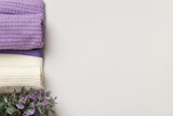 Rolled up white and purple waffle towels and a flower on a gray background.