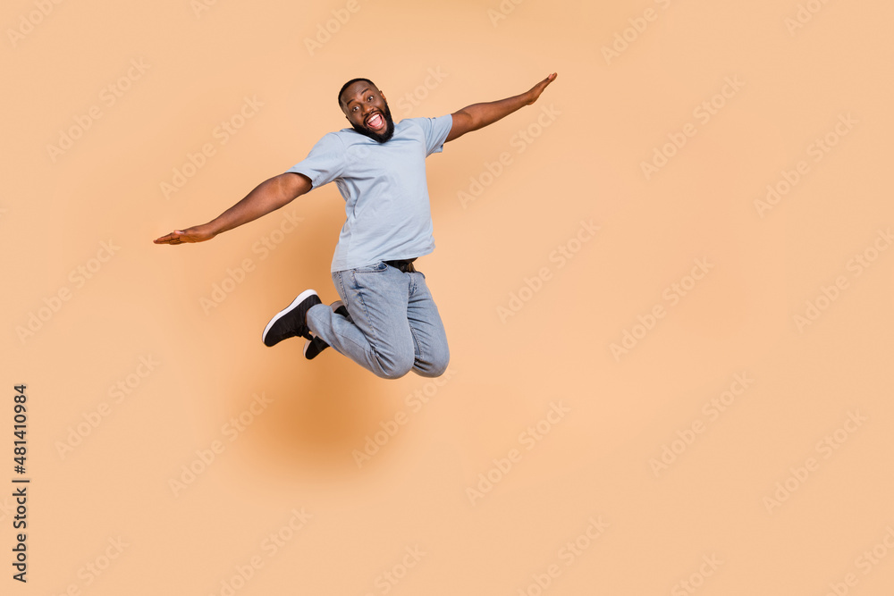 Full length body size view of attractive cheerful guy jumping flying having fun isolated over beige pastel color background