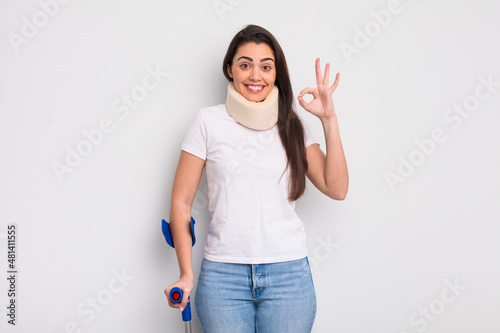 pretty hispanic woman feeling happy, showing approval with okay gesture. crash and physical injury concept