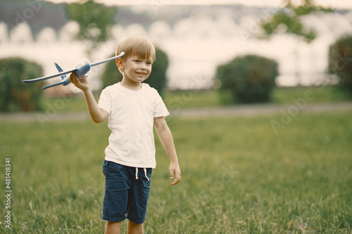 Little boy playing with airplane toy on a grass