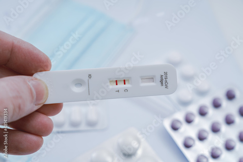 Posetive result by using rapid test device for COVID-19. Express corona test at home: Close up of man holding a negative covid antigen test.