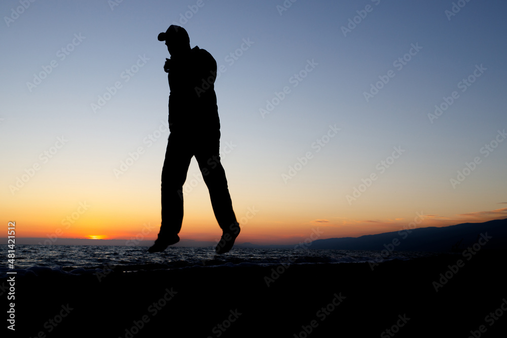 silhouette of a man in a jump over the coastline