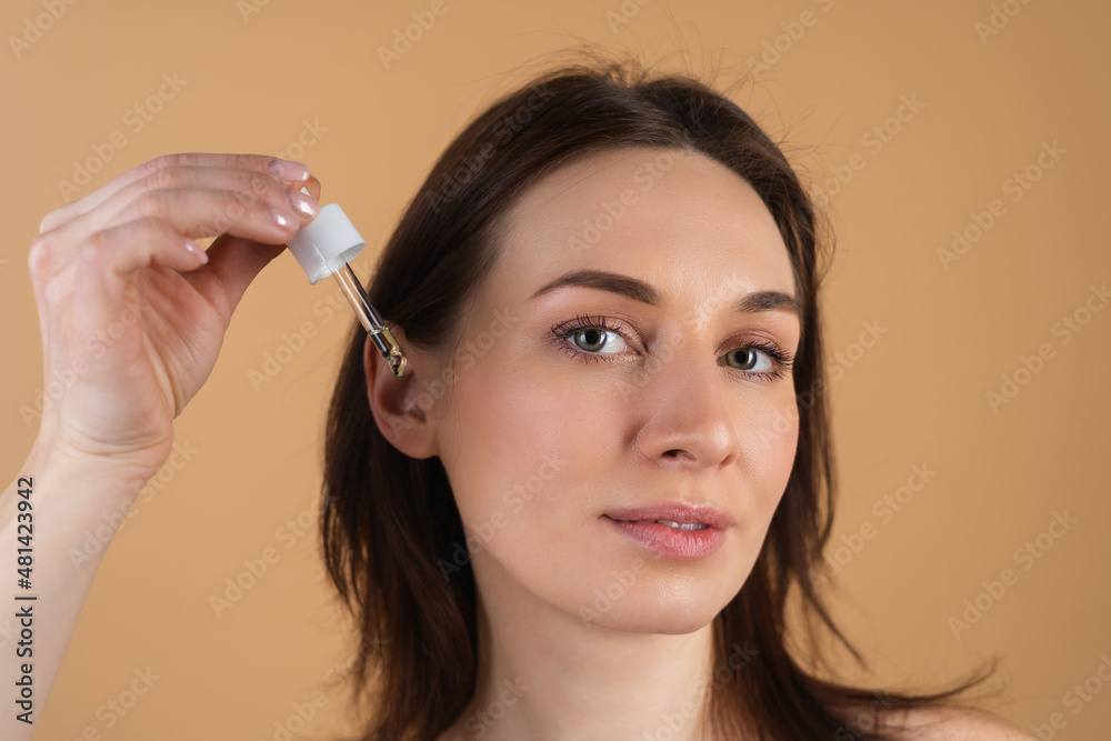 Obraz premium Close beauty portrait of topless woman with perfect skin and natural make-up, holds serum for youth and skin hydration, dropper with cosmetic oil.