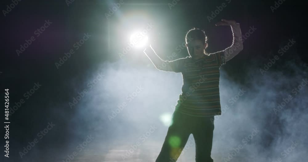 Young female dancer performing hip hop dance with strobe light and smoke background Young female dancer performing hip hop dance with strobe light and smoke background