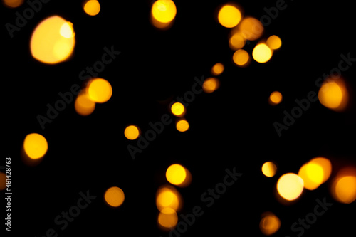 Gold bokeh on dark background. Defocused golden lights. New Year, Christmas background, abstract texture