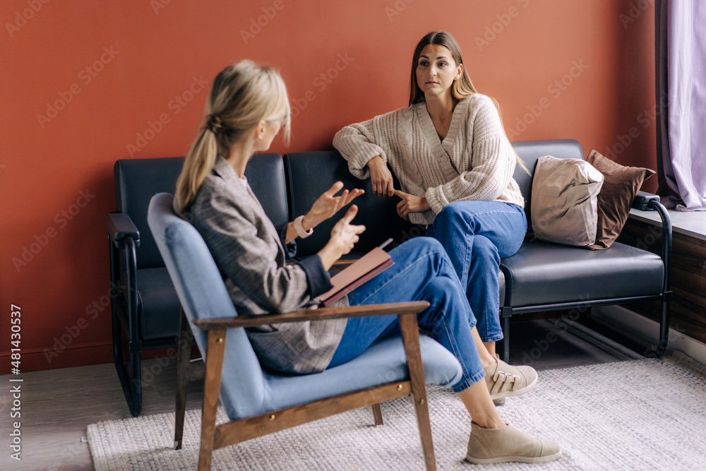 A female psychotherapist consults and gives advice and psychological support to a young female patient. - obrazy, fototapety, plakaty 