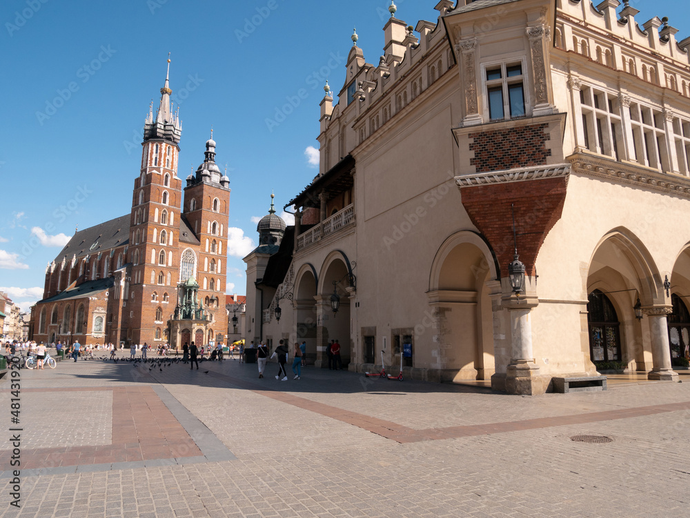 Fototapeta premium Famous Saint Mary's Basilica (Mariacki Church Kraków) and Sukiennice (The Cloth Hall) at the Main Market Square in the Old Town district of Krakow, Poland.