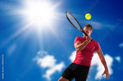 Youyng man Holding A Paddle Tennis Racket Hitting The Ball On A Blue Background. © BillionPhotos.com