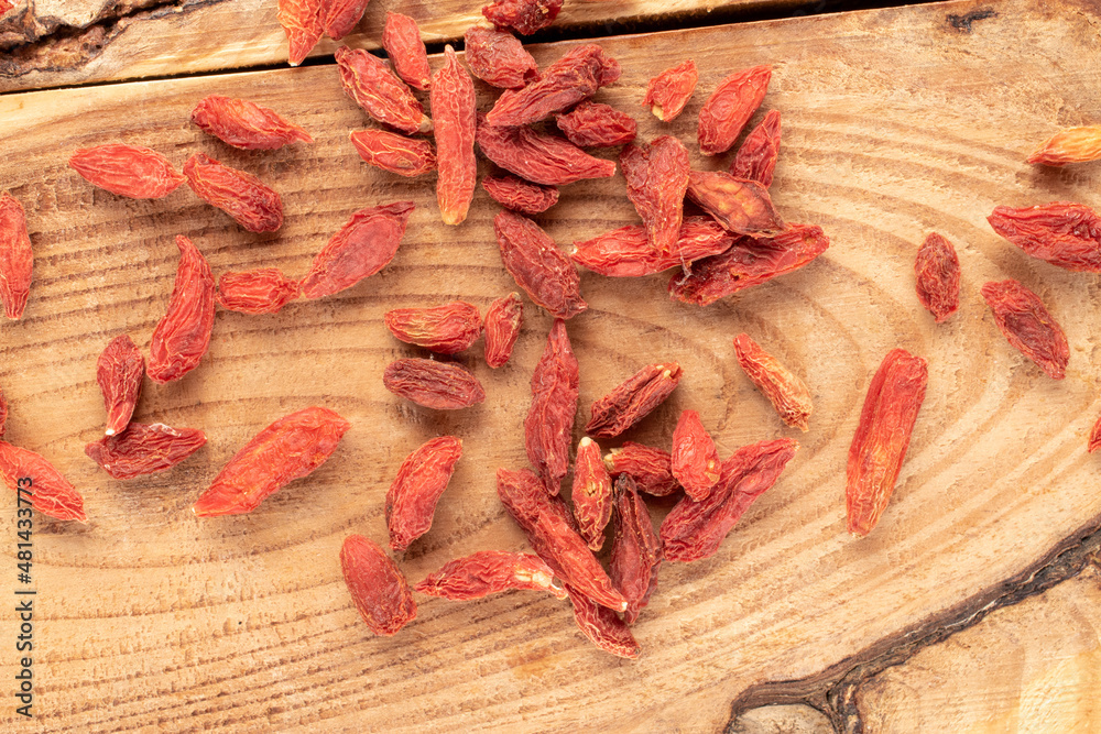 Dried organic goji berries on a wooden table, macro, top view.