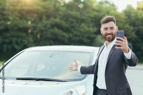 Foto Successful and happy man brags about buying a new car, having fun talking to fri