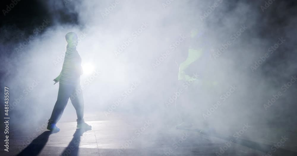 Two young female dancers performing hip hop dance in slow motion with light and smoke background Two young female dancers performing hip hop dance in slow motion with light and smoke background