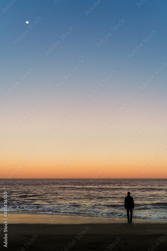 man walking on the beach at dusk