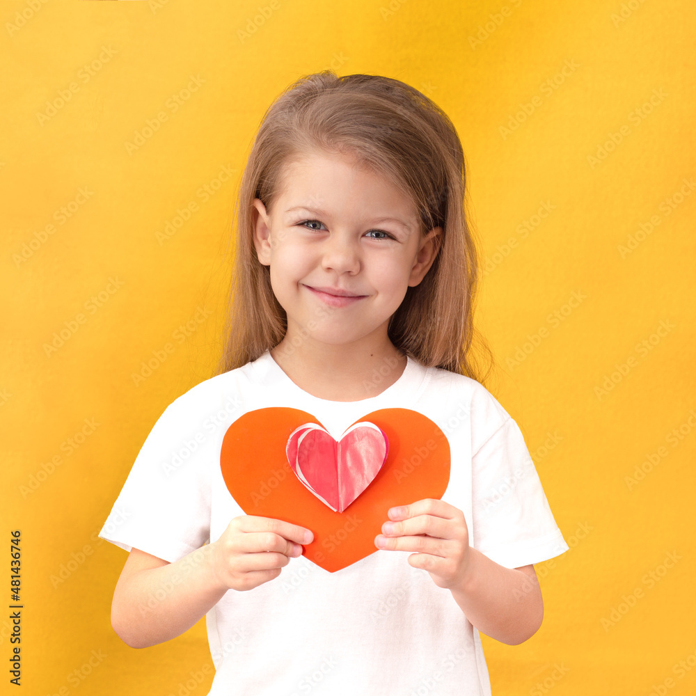 Child kid holding red heart to St Valentine day handmade from paper, on yellow background waist up caucasian little girl of 5 years in white t-shirt Child kid holding red heart to St Valentine day handmade from paper, on yellow background waist up caucasian little girl of 5 years in white t-shirt