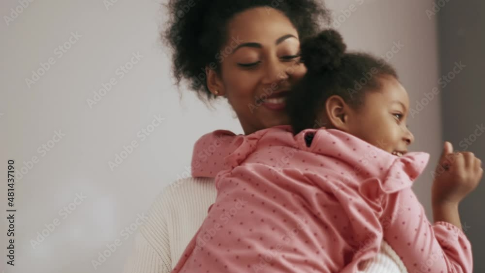 Lovely African mother hugging her daughter and holding her on the hands at home Lovely African mother hugging her daughter and holding her on the hands at home