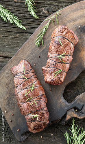 Roasted beef tenderloin steaks on wooden board on table