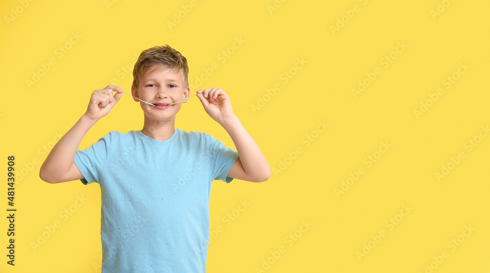 Little boy in blue t-shirt chewing gum on yellow background Little boy in blue t-shirt chewing gum on yellow background