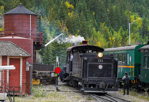 Georgetown, Colorado - 9-19-2021:  a vintage steam locomotive on the Georgetown Loop Railroad line in Georgetown Colorado, preparing to take on water from a vintage wooden water tower photo