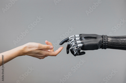 the human hand and the siber hand bionic prosthesis make a handshake and greeting. modern technologies of prosthetics of limbs of hands and feet. full life of people with amputated limbs. black bionic photo