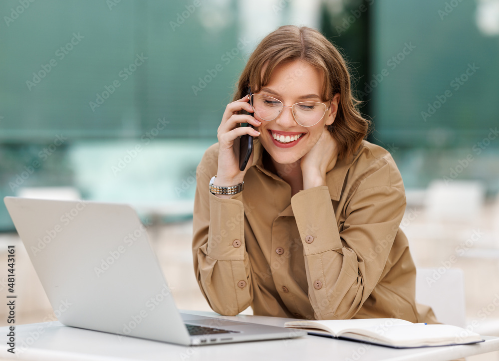 Happy young office assistant working remotely online sitting with laptop and coffee outside Happy young office assistant working remotely online sitting with laptop and coffee outside