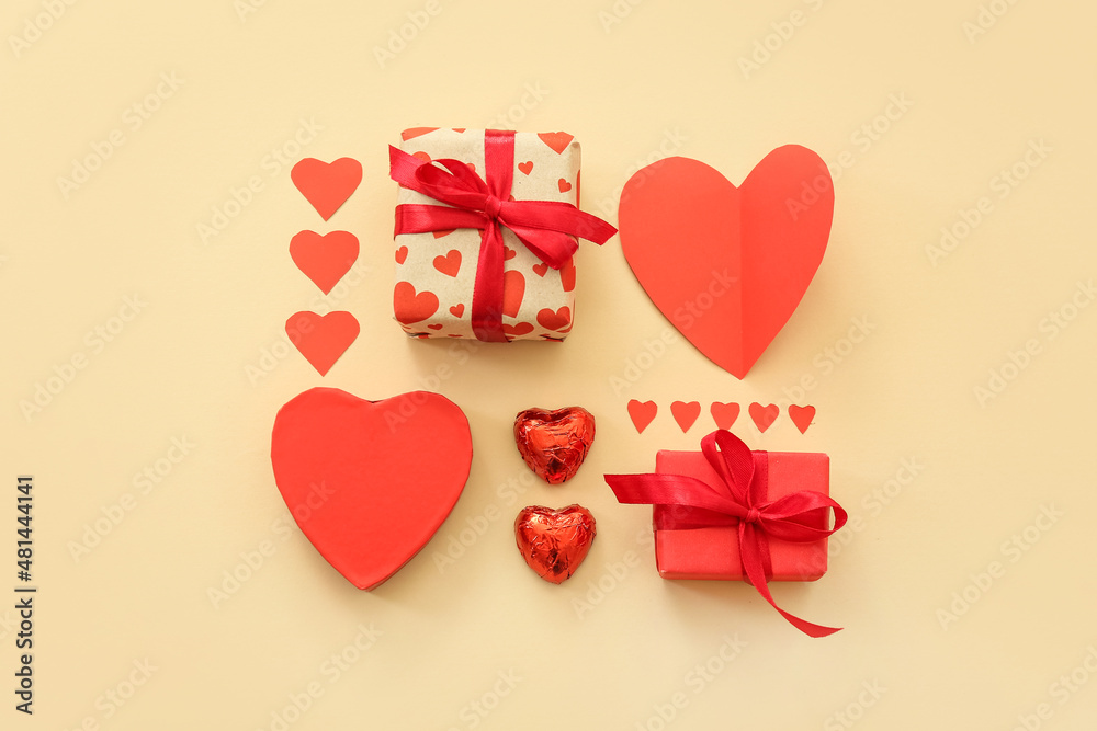 Beautiful composition with gift boxes, paper hearts and candies on beige background. St. Valentine's Day