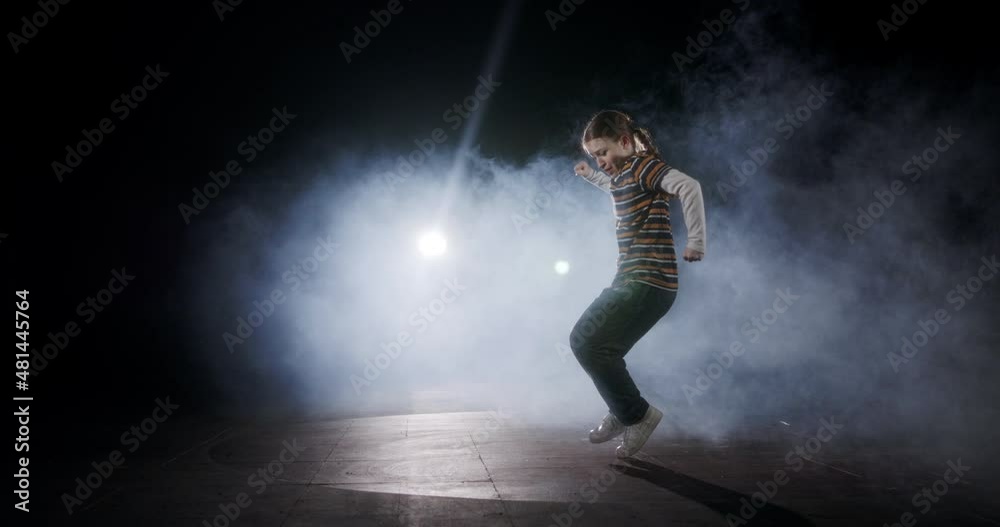 Teenage female dancer performing hip hop dance in slow motion with strobe light and smoke background Teenage female dancer performing hip hop dance in slow motion with strobe light and smoke background