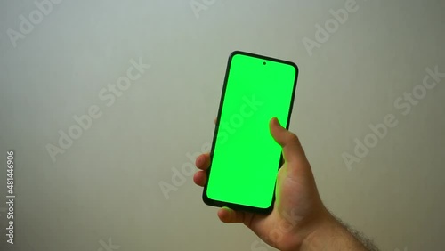 Man using smartphone viewing green screen scrolling on mobile phone browsing chroma key . close up male hands . Mobile phone mock-up
