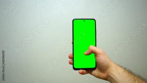 Man using smartphone viewing green screen scrolling on mobile phone browsing chroma key . close up male hands . Mobile phone mock-up