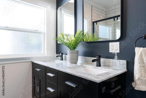 Photo Detail of modern bathroom vanity with marble counter top, double sinks with black faucets, black cabinetry and matching black framed mirrors