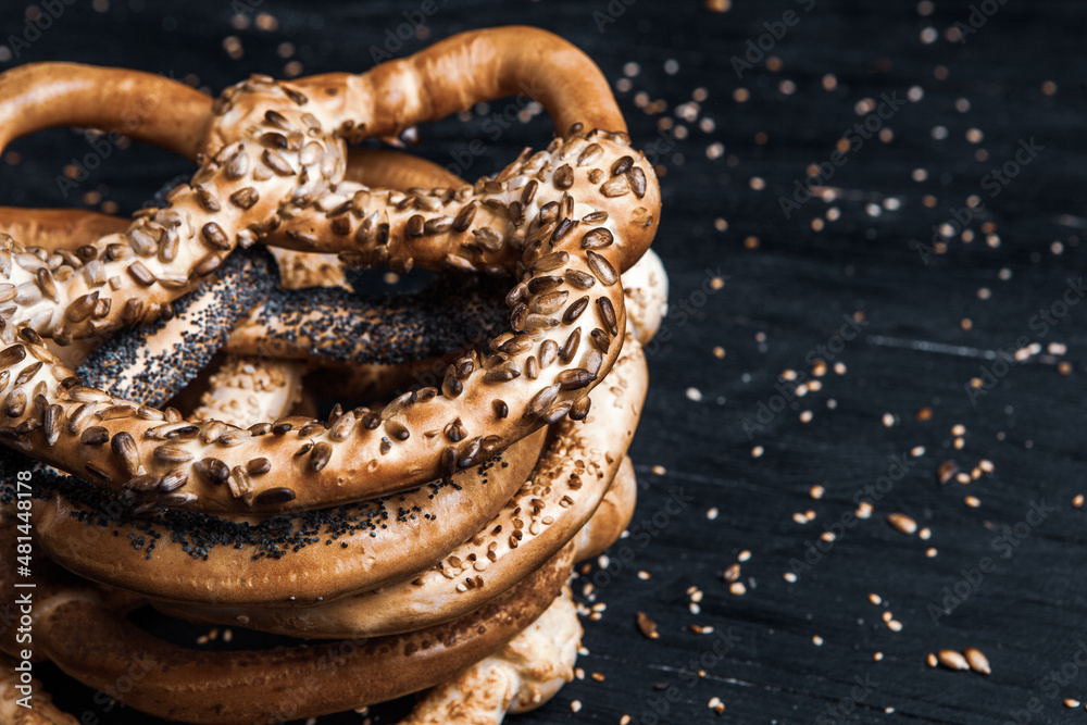 Fresh prepared homemade soft pretzels. Different types of baked pretzels with seeds on a black background