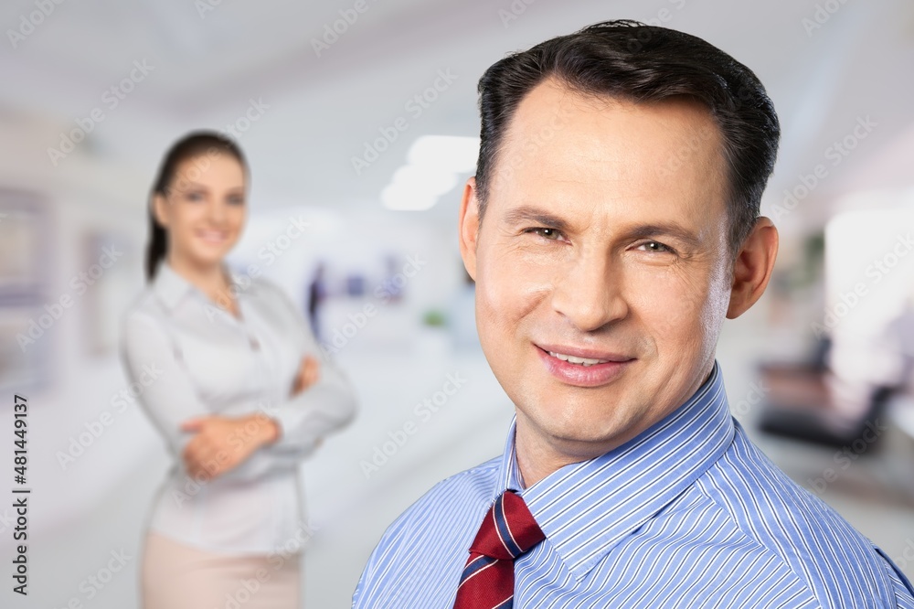 A couple of smiling business people on the office background A couple of smiling business people on the office background