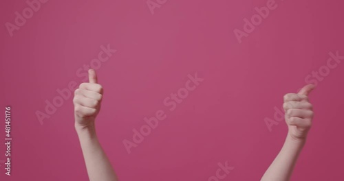 Woman points thumb up against an isolated pink background.Approval hand gestures photo