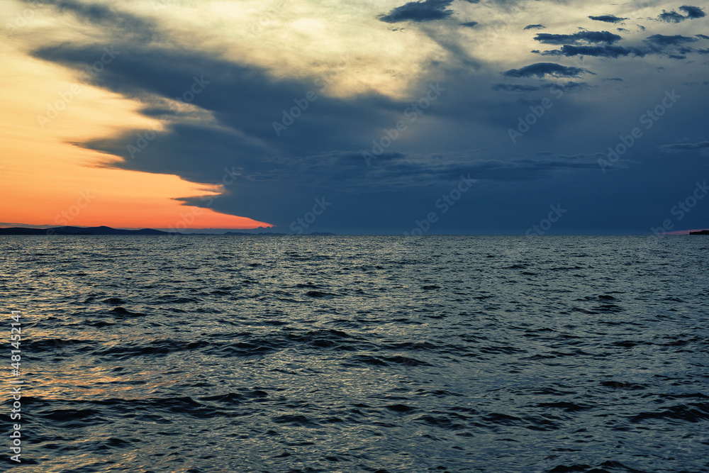 Obraz premium Beautiful sunset at sea, dramatic clouds on orange sky at evening 