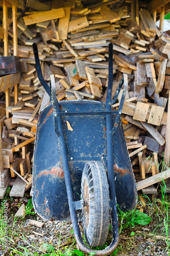 Wheel Barrow in Garden with a lot of wood