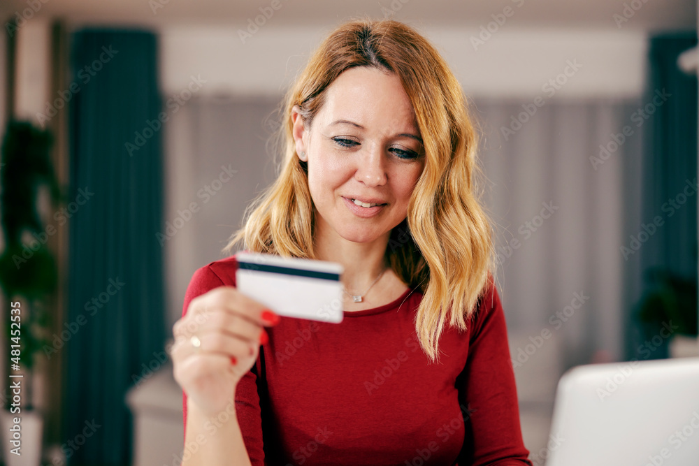 A happy woman using credit cart for online shopping from her cozy home. A happy woman using credit cart for online shopping from her cozy home.