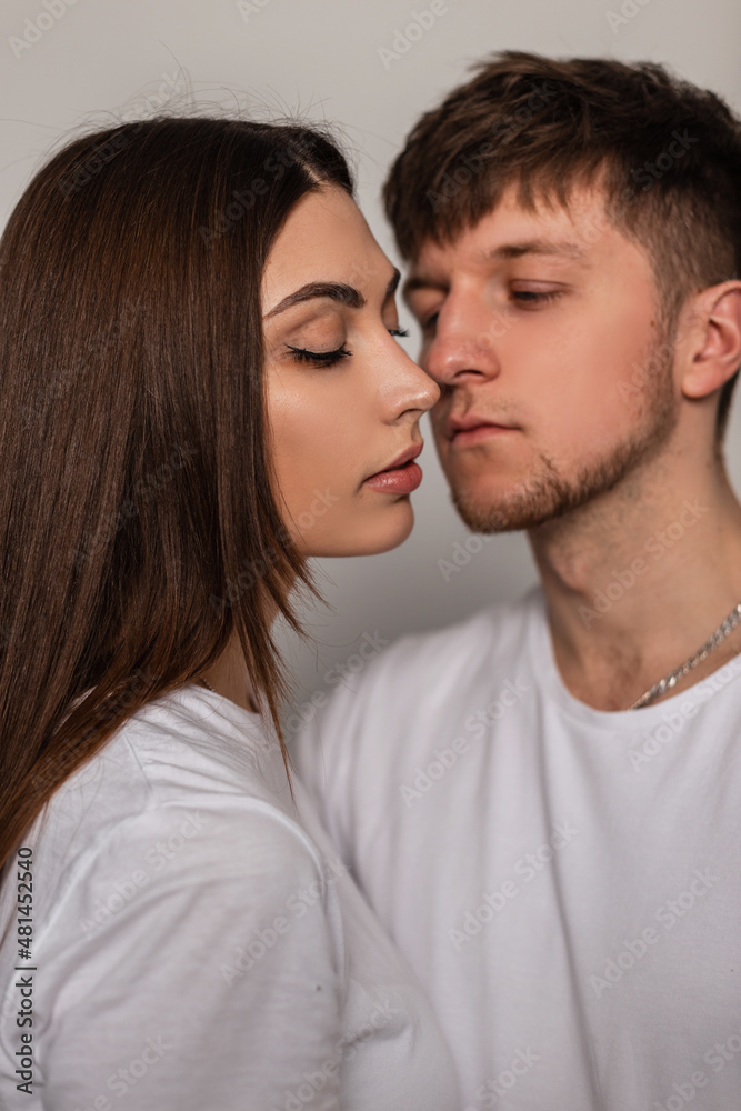 Beautiful young love couple man and woman in white fashionable t-shirts in studio Beautiful young love couple man and woman in white fashionable t-shirts in studio