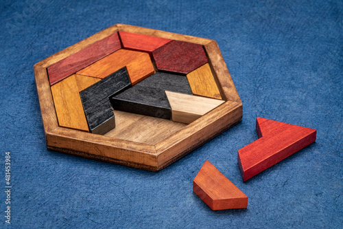 Foto wooden hexagon tangram puzzle against textured handmade bark paper, brain teaser