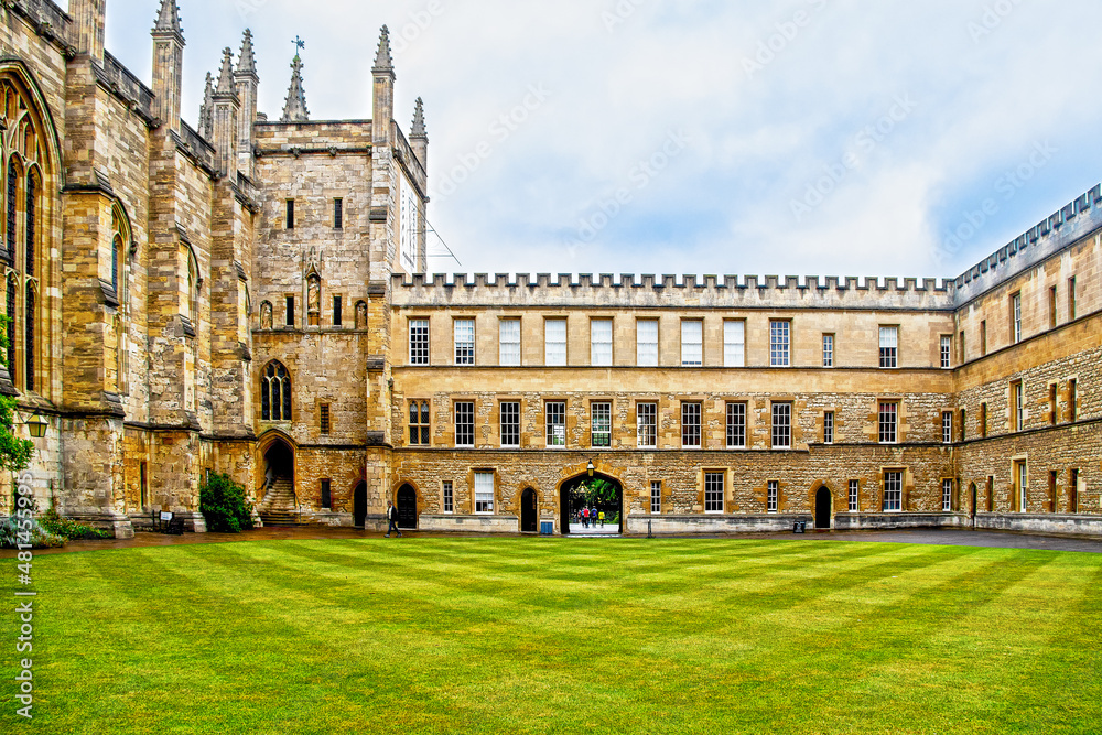 07-2019 Oxford UK - The New College quad with criscross mowed grass and some students going through arch on pretty summer day at Oxford University.