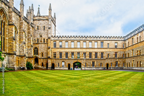 07-2019 Oxford UK - The New College quad with criscross mowed grass and some students going through arch on pretty summer day at Oxford University.