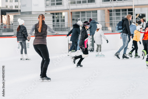 Soft,Selective focus.People, friendship, sport and leisure concept - happy friends on skating rink.Group of teenage friends ice skating on an ice rink © Nataliia