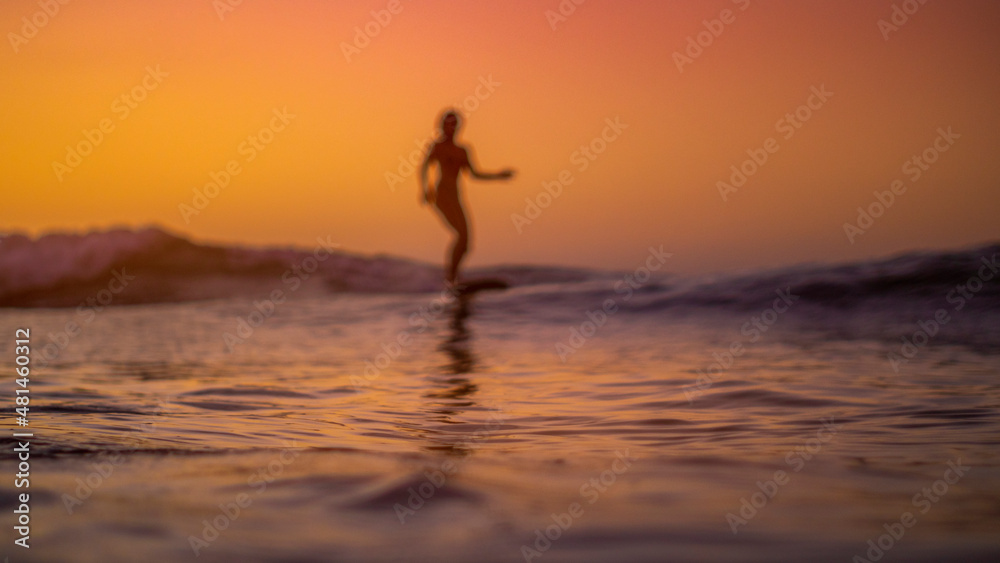 Silhouette of a woman surfing at sunset
