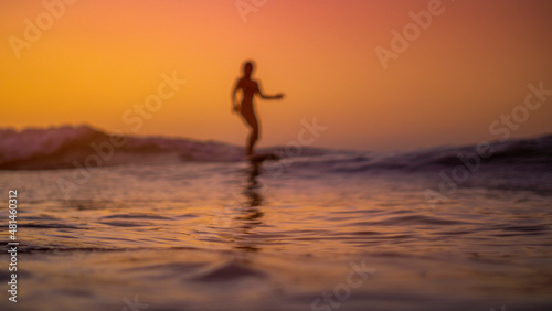Silhouette of a woman surfing at sunset