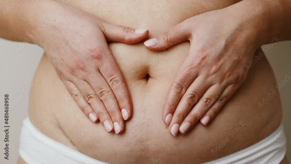 Plus size woman in underwear holding hands on abdominal area forming heart shape around navel Plus size woman in underwear holding hands on abdominal area forming heart shape around navel