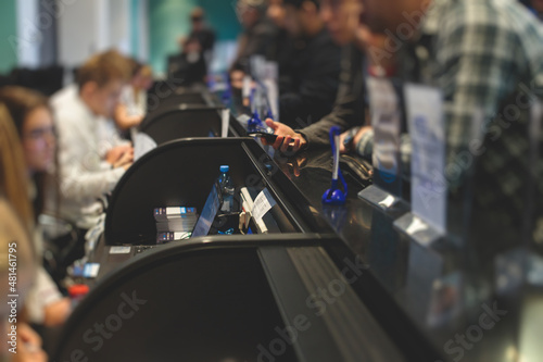 Process of checking in on a conference congress forum event, registration desk table, visitors and attendees receiving a name badge and entrance wristband bracelet and register electronic ticket,