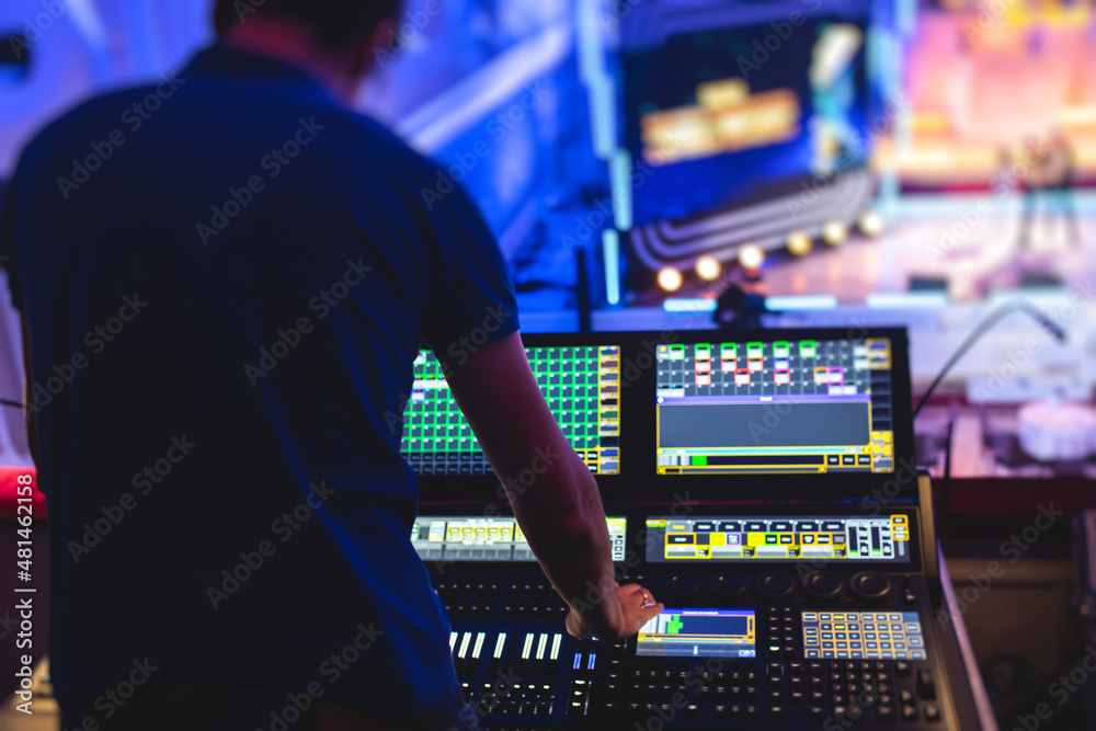 View of lighting technician operator working on mixing console