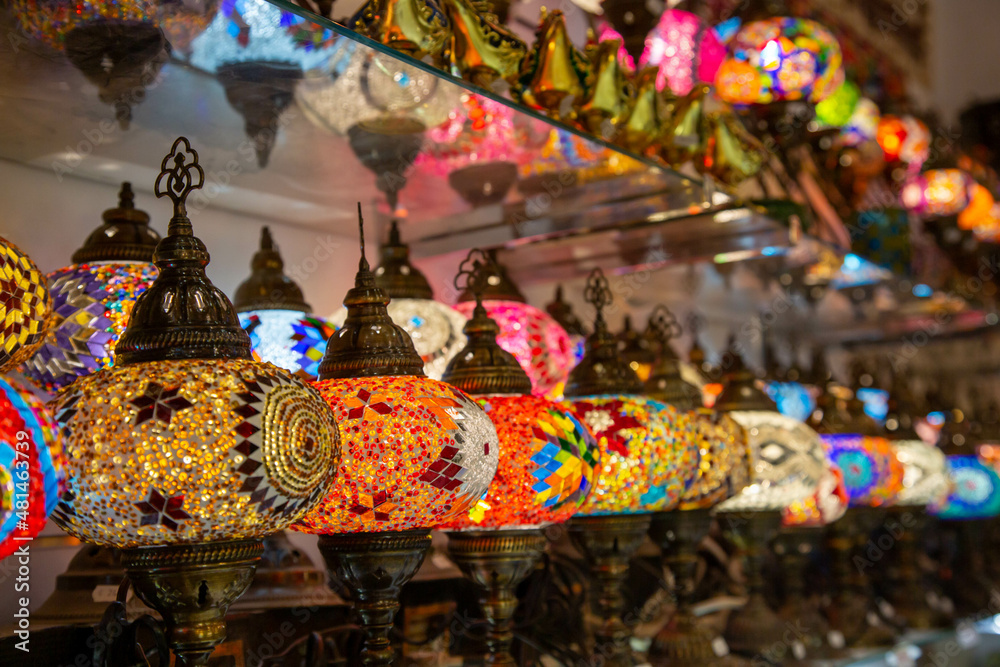 Electric lamps with beautiful multi-colored shades in the oriental style are presented for sale on the store shelf.