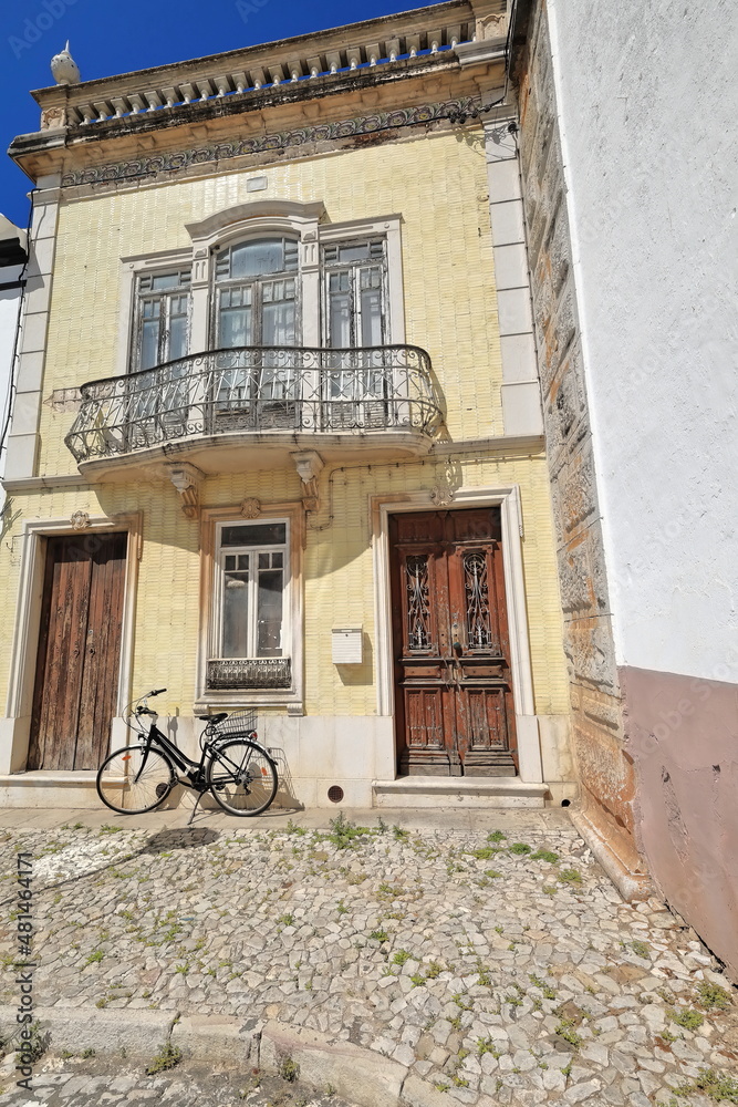 Yellow tile facade-Neoclassical townhouse-chipped wooden doors-metal railing balcony-black bicycle. Tavira-Portugal-066