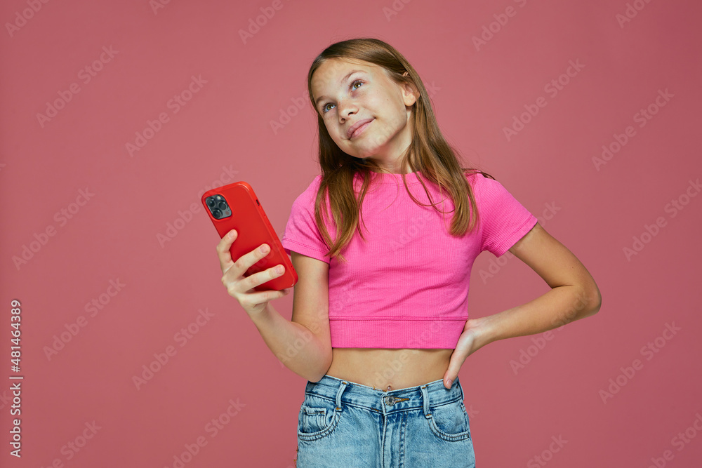 Pensive dreaming child girl hold phone looking up on pink background. Children gadget addiction. E-learning mobile apps Pensive dreaming child girl hold phone looking up on pink background. Children gadget addiction. E-learning mobile apps