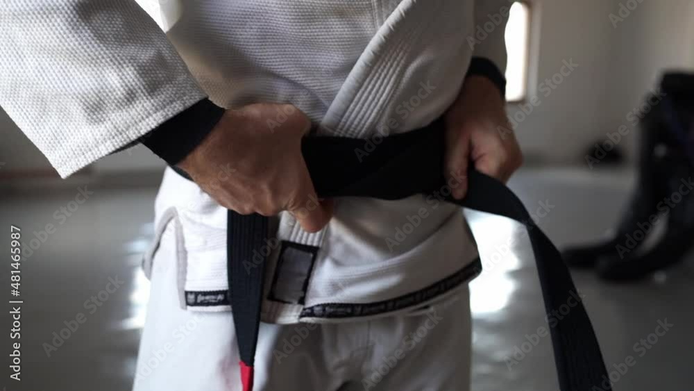 brazilian jiu jitsu bjj black belt male athlete holding belt tie around waist adjusting knot brazilian jiu jitsu bjj black belt male athlete holding belt tie around waist adjusting knot