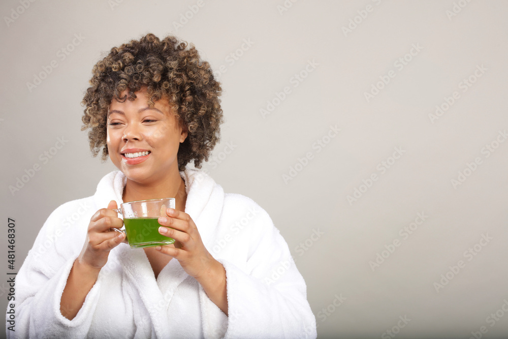 Studio shot of woman in bathrobe drinking green tea Studio shot of woman in bathrobe drinking green tea