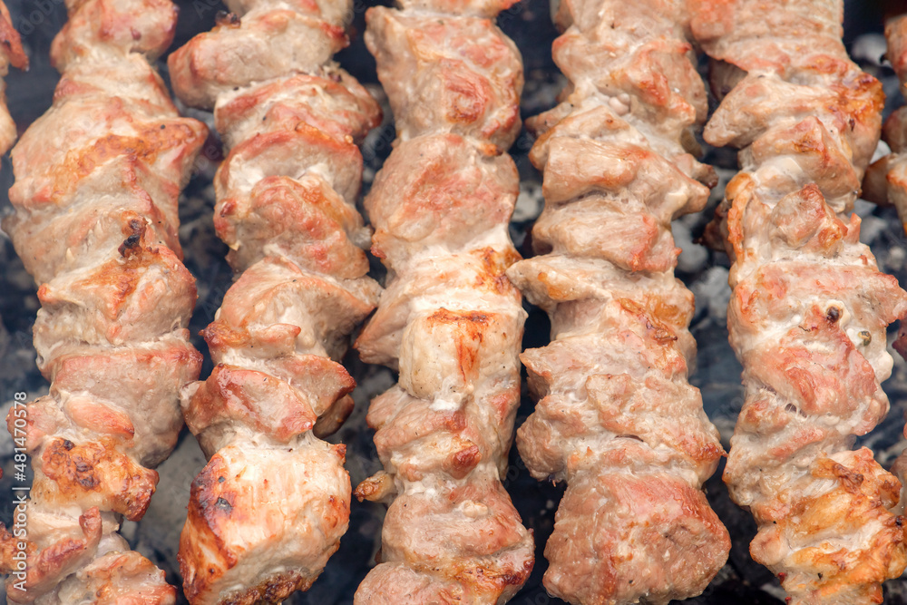 Grilled pork meat on metal skewers. Barbecue cooking. The smoke from the coals develops over the meat. Promotional banner for menu with copy space to insert text